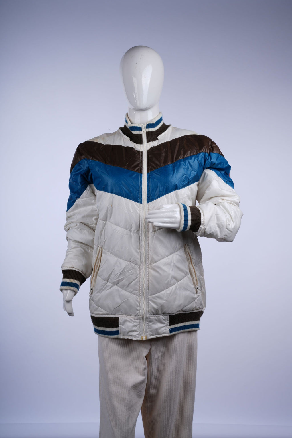 Retro-inspired white puffer jacket featuring teal and dark brown stripes, zip closure, and ribbed hem for casual outdoor wear.