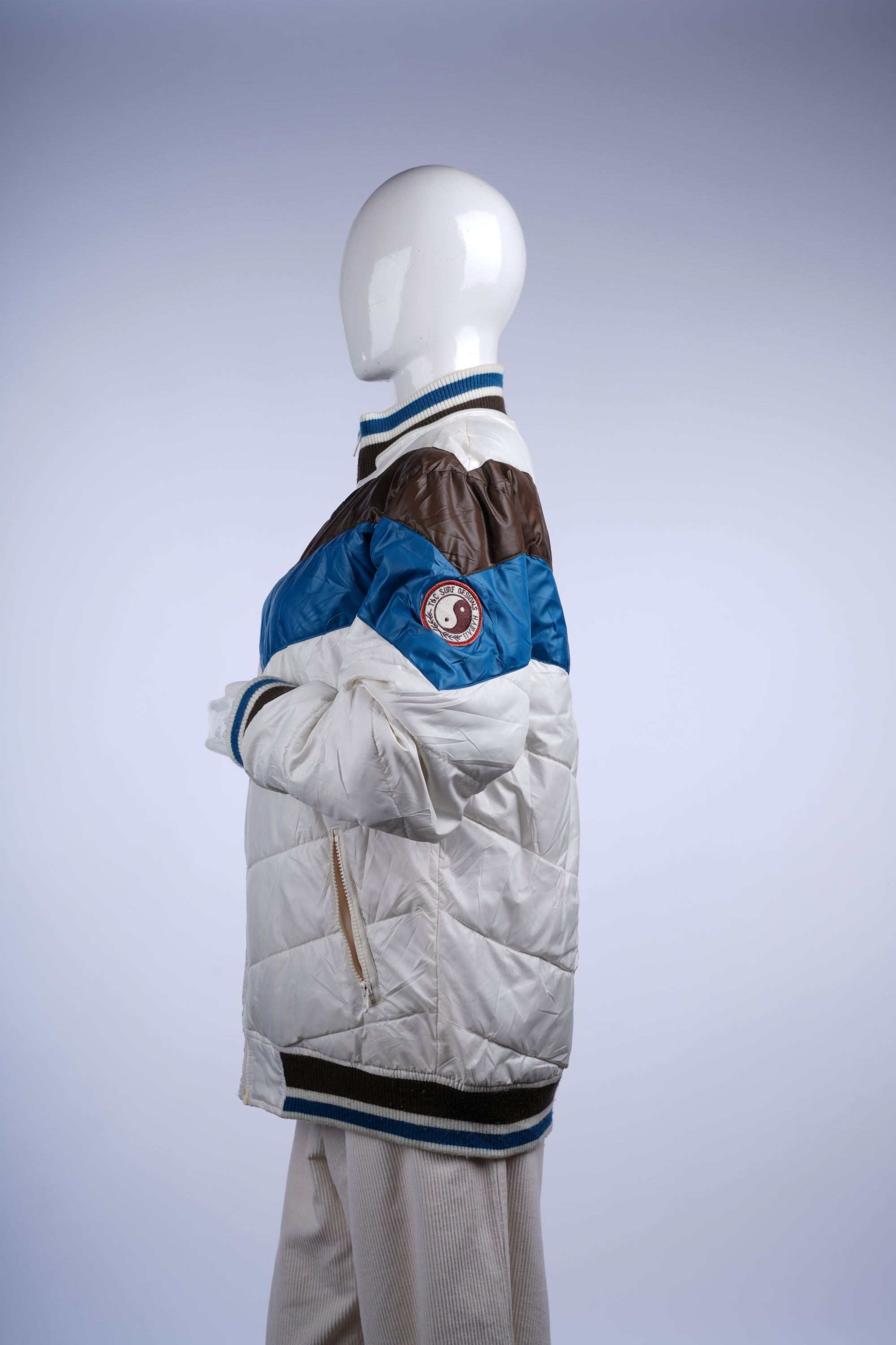 White vintage puffer jacket with colorful horizontal stripes, full-zip front, and ribbed cuffs, ideal for retro casual style.