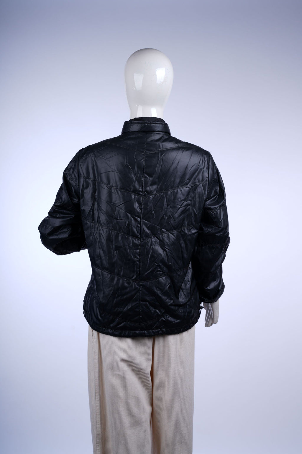 Casual black quilted jacket with full zip, stand collar, and zippered pockets, offering warmth and style.