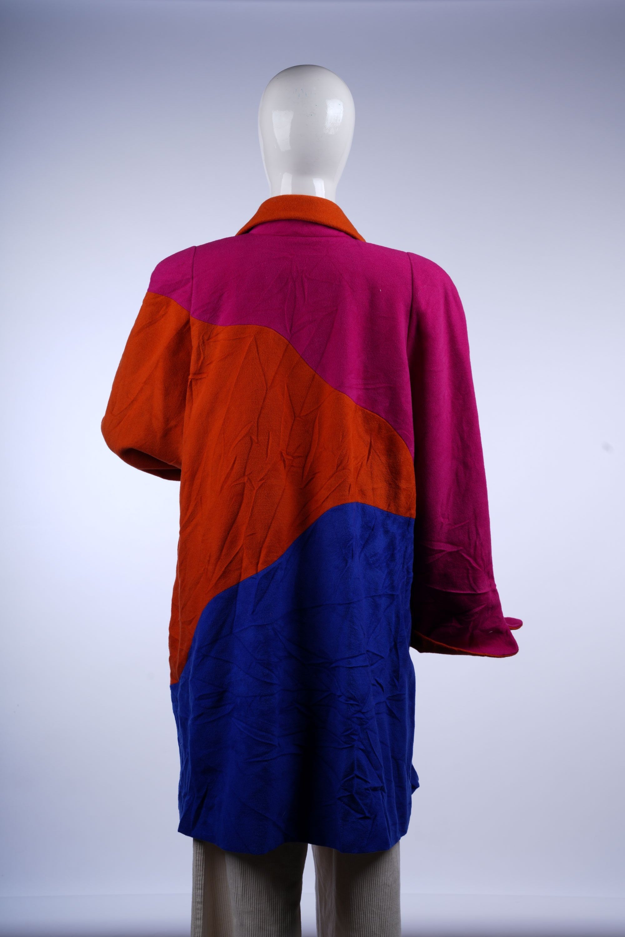 Striking retro color-block coat with collared neckline and contrasting buttons in vivid pink, orange, and royal blue.