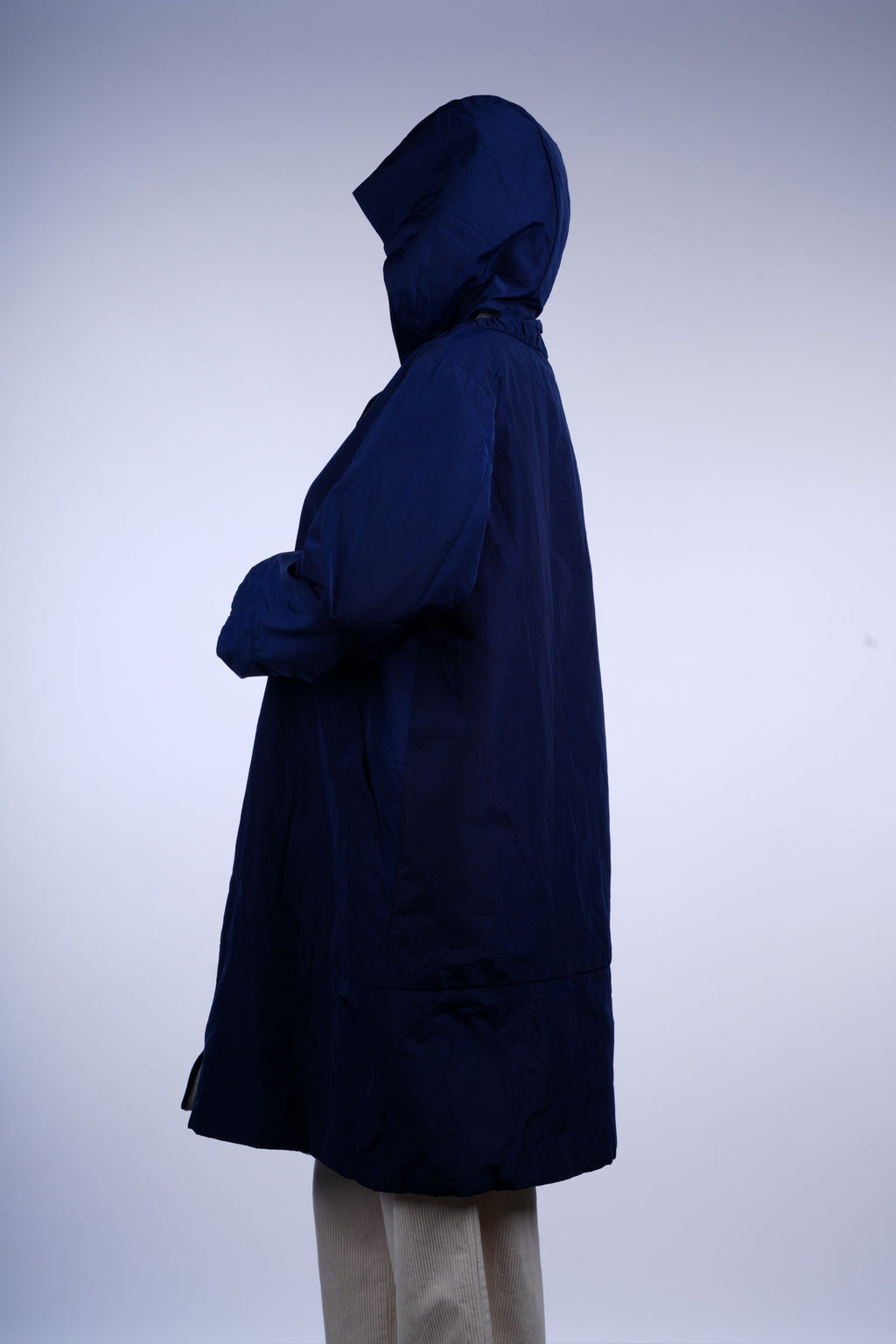 Water-resistant blue longline rain jacket with hood and full zipper, offering functional and stylish wet-weather coverage.