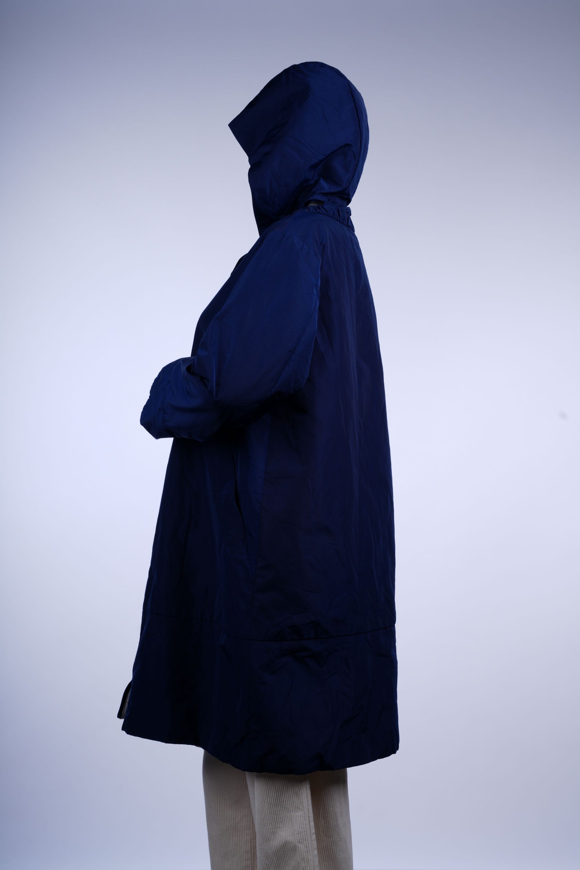 Water-resistant blue longline rain jacket with hood and full zipper, offering functional and stylish wet-weather coverage.