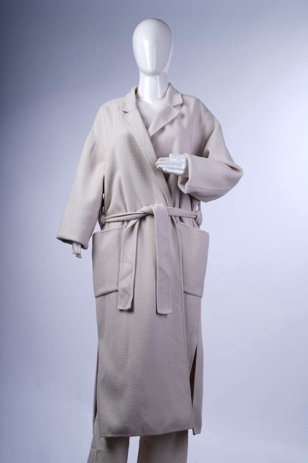 Chic cream overcoat featuring a longline silhouette, patch pockets, and timeless lapels for effortless layering.