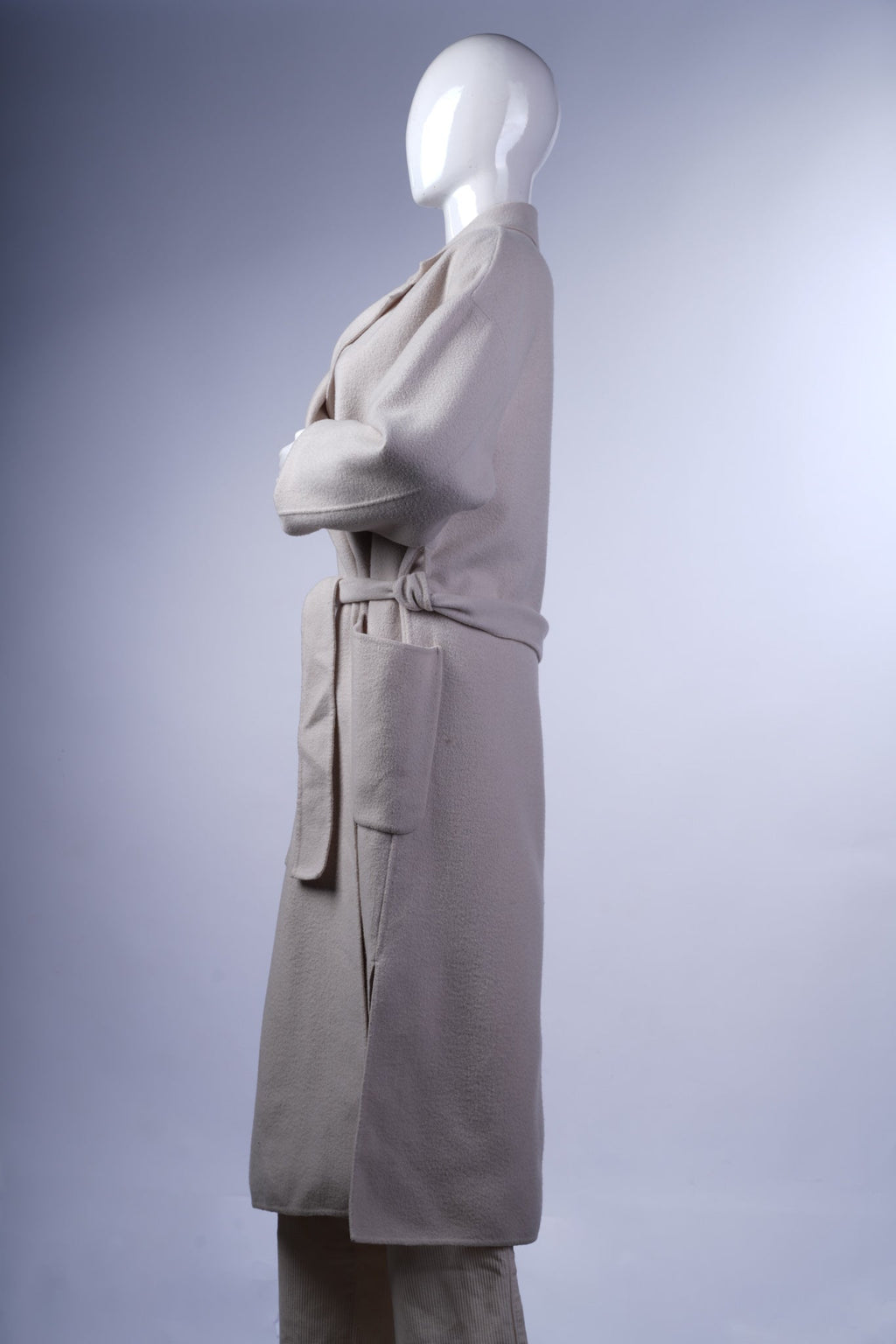 Elegant cream longline coat with relaxed fit, classic lapel, and functional patch pockets, ideal for stylish layering.