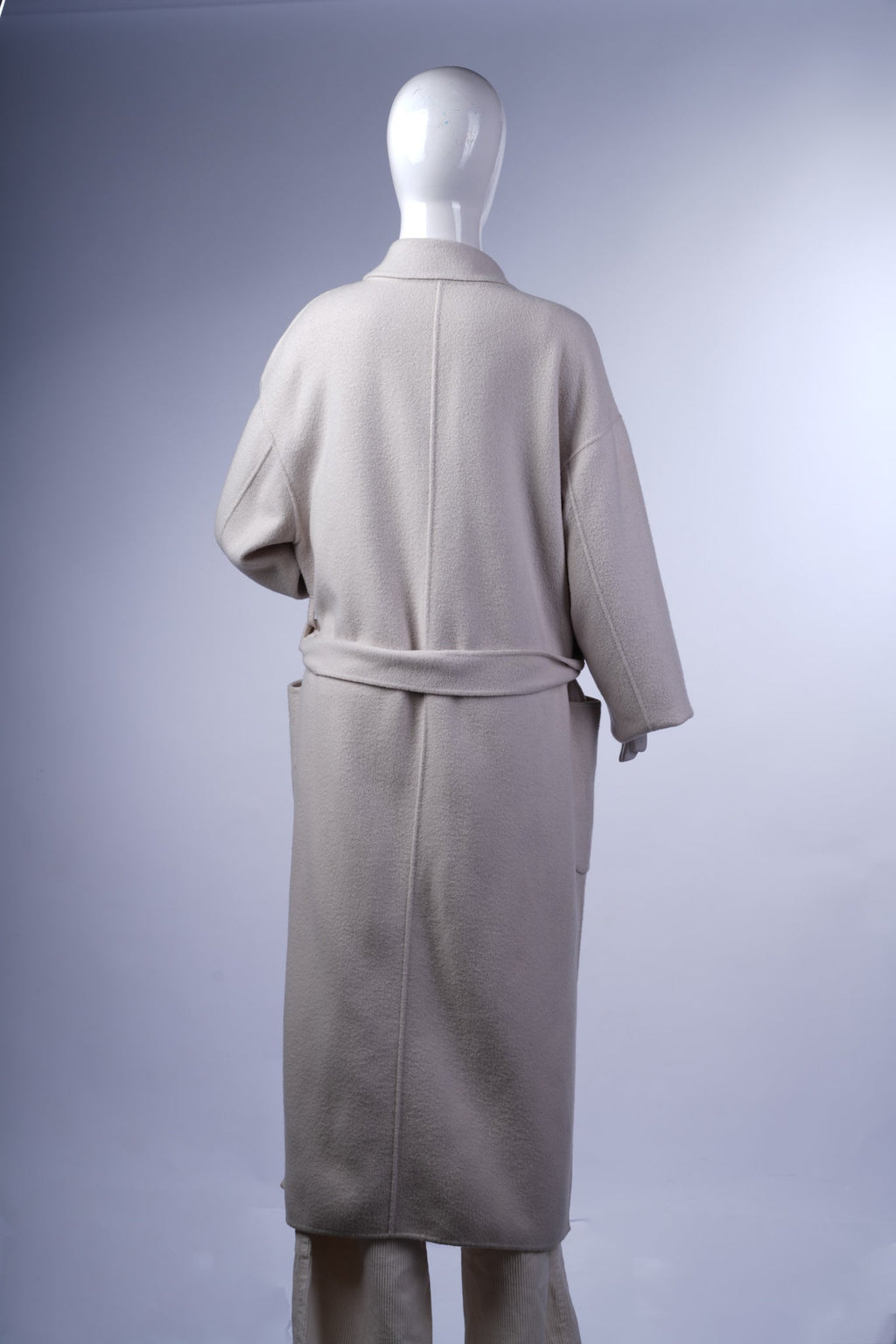 Cozy cream longline coat with traditional lapels, patch pockets, and a relaxed silhouette for versatile wear.