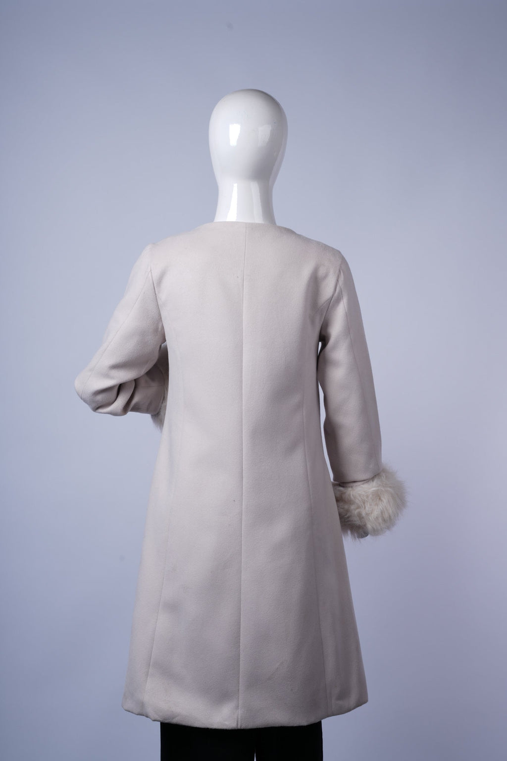 Chic off-white coat with faux fur-trim cuffs, round neckline, and concealed front closure, perfect for formal or semi-formal occasions.