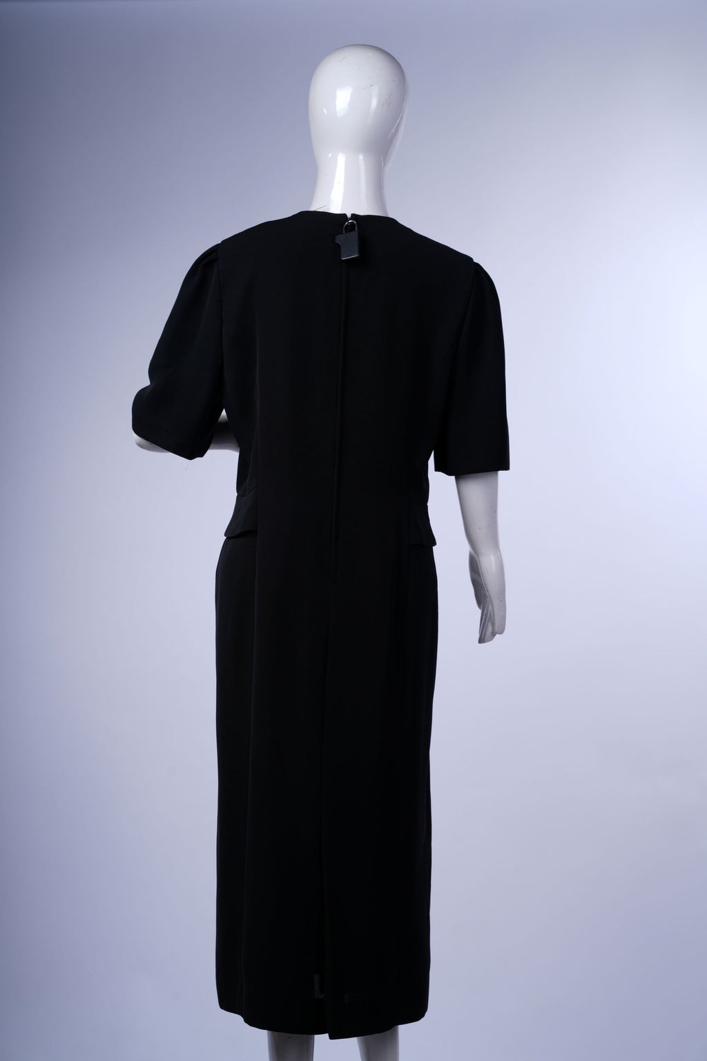 Modern black midi dress with long sleeves and front slit, combining elegance and contemporary style.