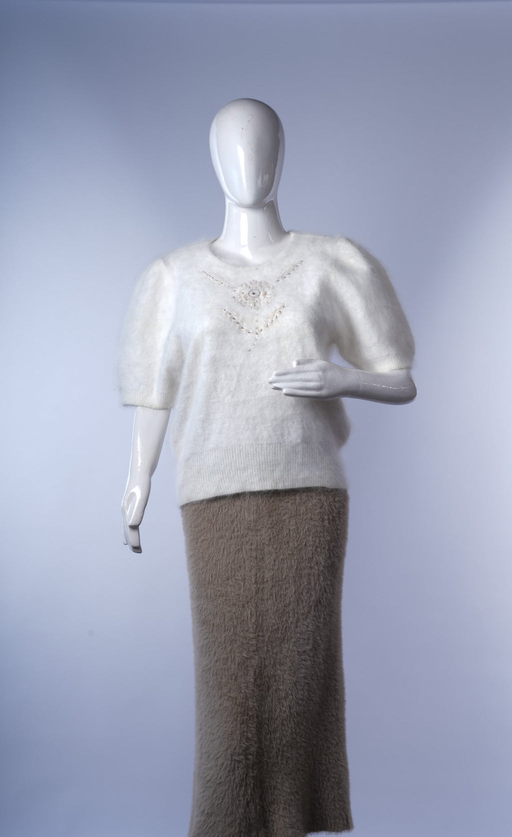 Soft white knit top featuring round embellished collar for elegant casual wear.