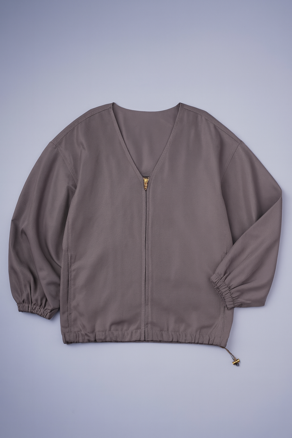 Sleek minimalist jacket with full zipper, side pockets, and elastic cuffs and hem, ideal for spring layering.