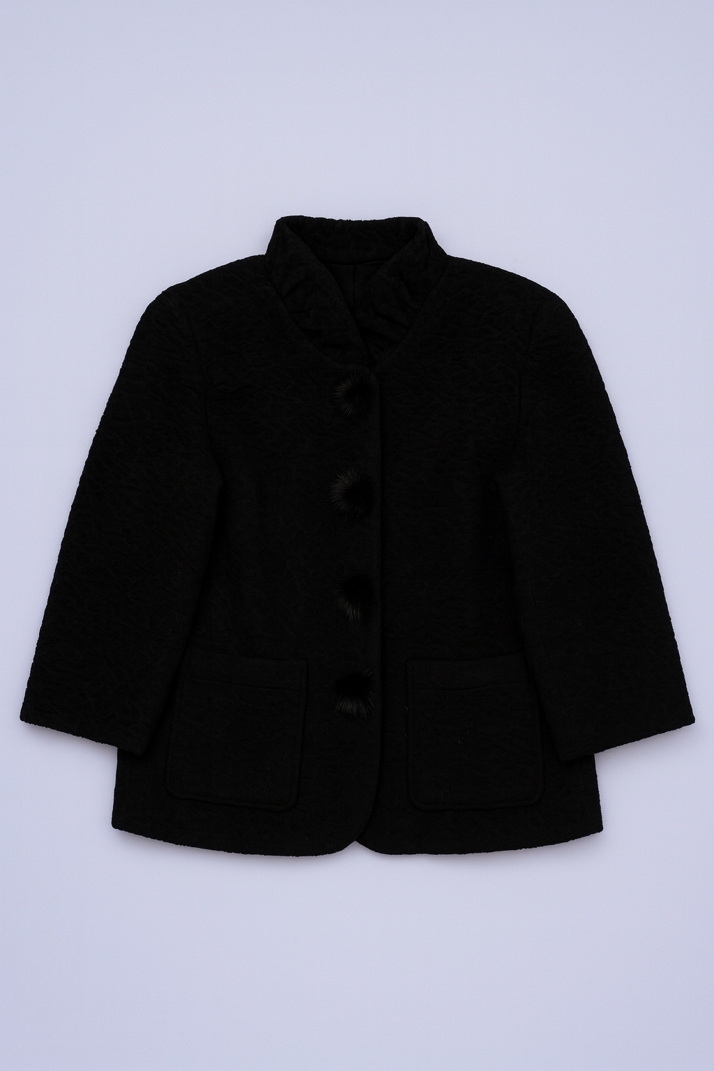 Black tailored coat with high collar, ornate button closure, and flap pockets.