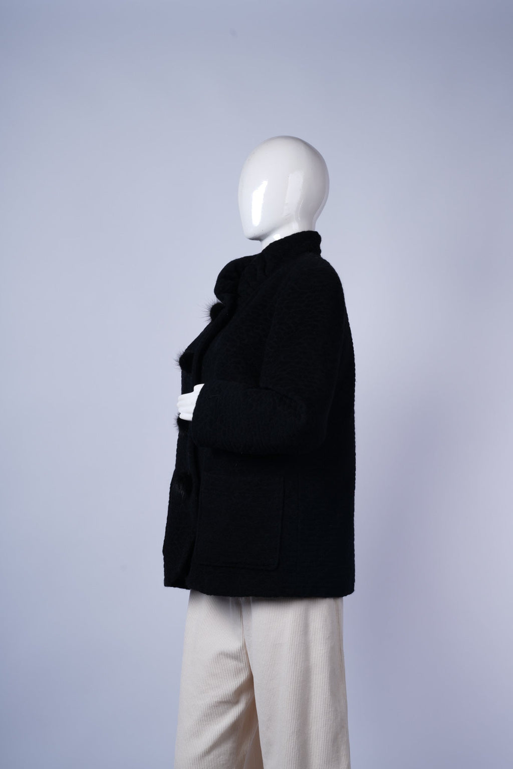 Elegant black coat with tailored fit, flap pockets, and decorative buttons.