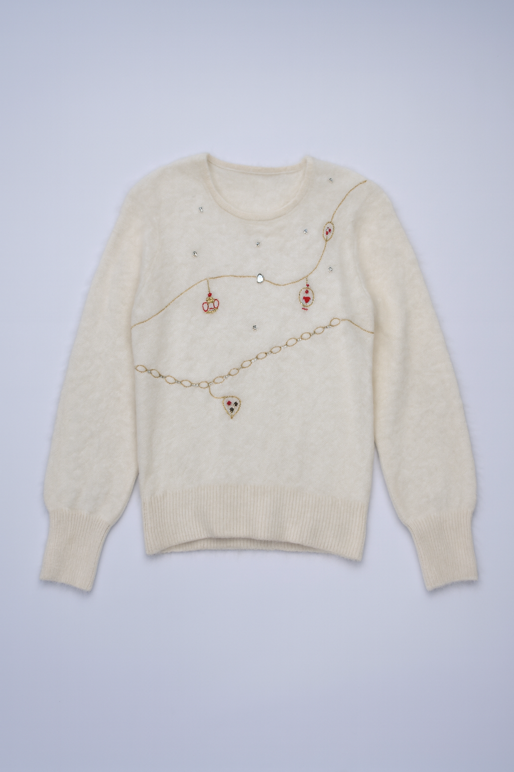 Cream knit sweater featuring gold-toned chains, pearls, and charms.