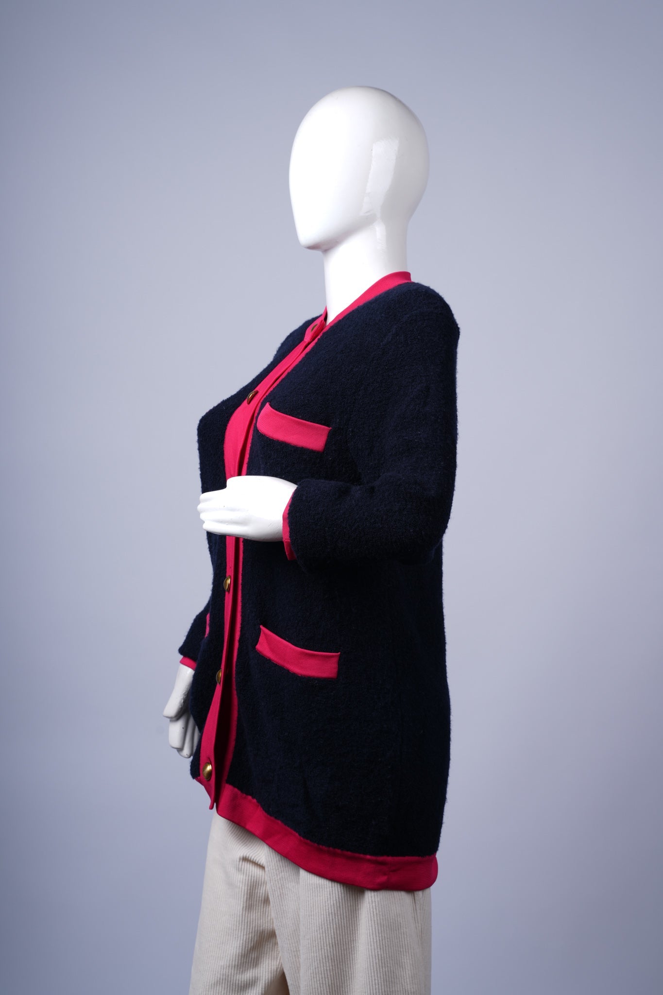 Statement navy knitwear with decorative buttons and contrasting red edges.