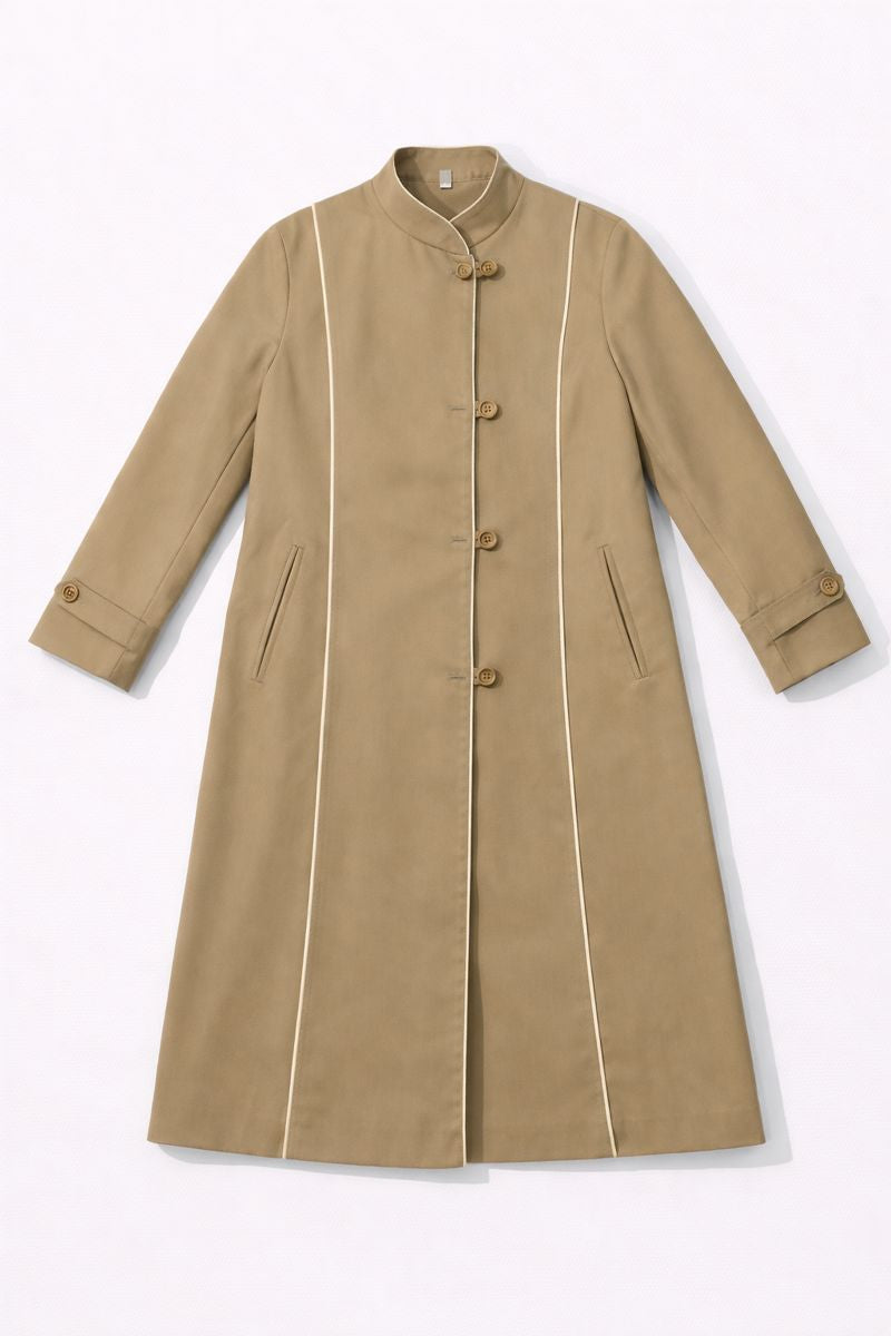 Knee-length mandarin-collar coat with subtle ribbed texture, white piping along front seams and cuffs, and adjustable buttoned cuffs